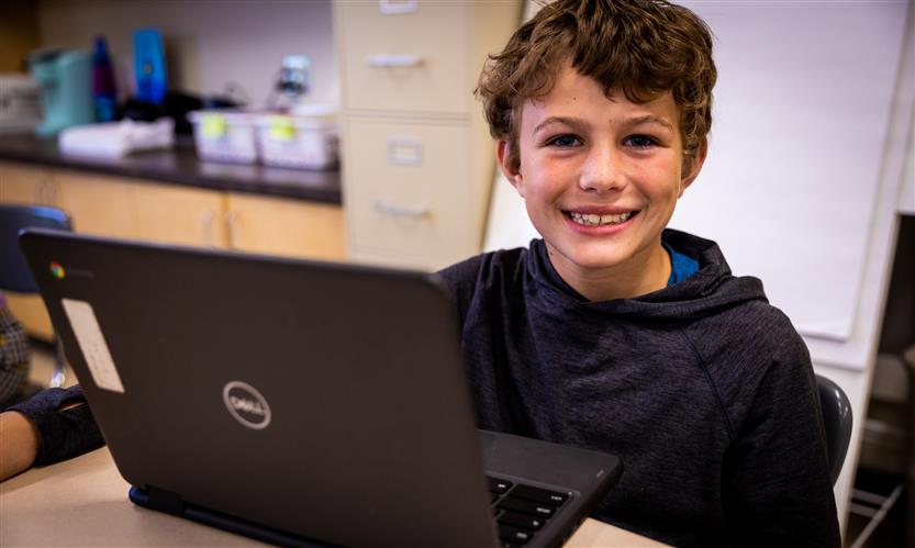 A boy with curly hair and a black shirt smiles
